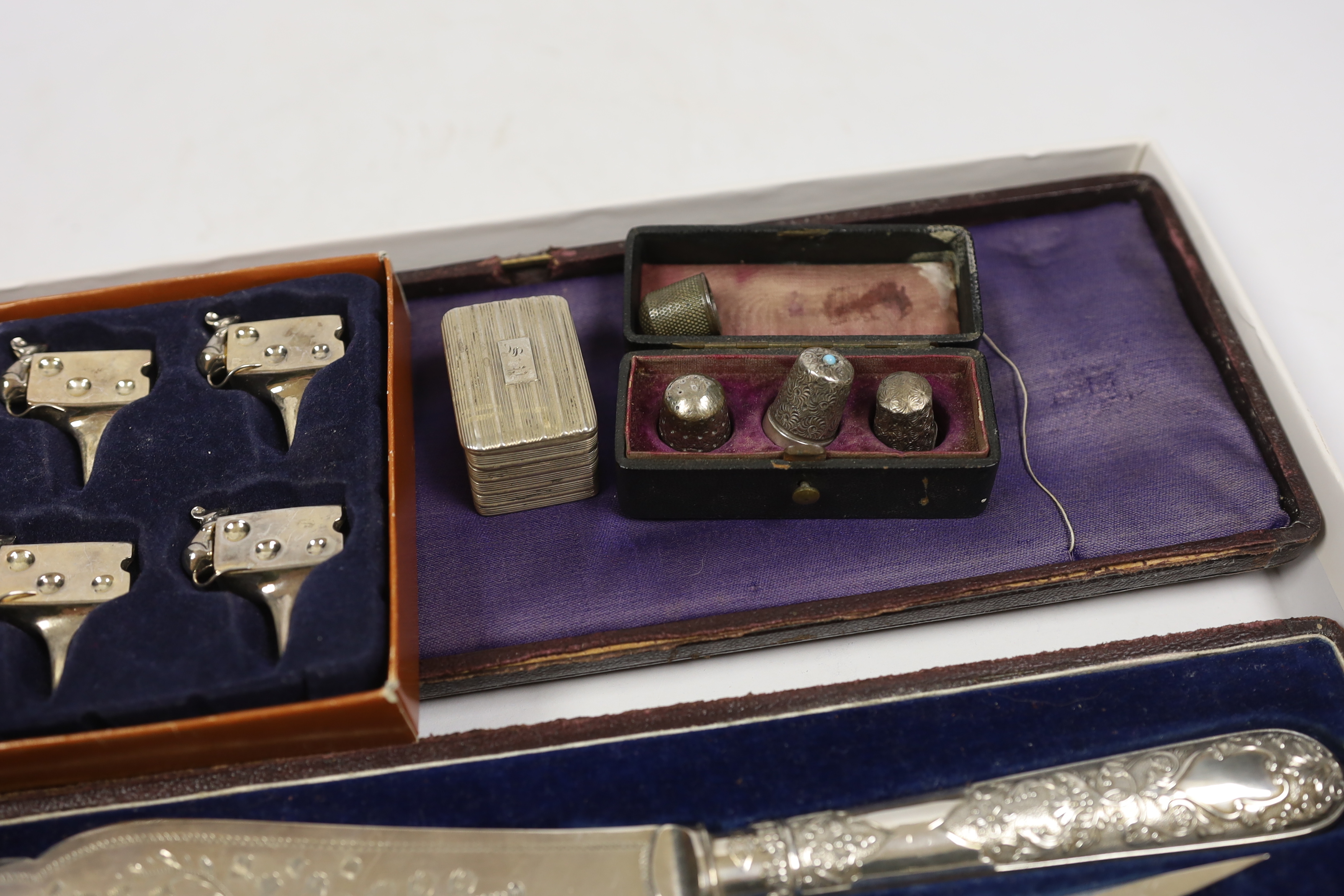 A George III silver nutmeg grater(lacking rasp), Birmingham, 1816, 42mm, together with four assorted thimbles, two silver, a based pair of silver plated fish servers and a set of four metal cheese card holders.